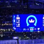 A blue lighted jumbotron showing the score is tied between the two teams 2-2.