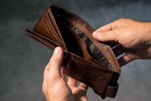 Two hands holding an empty brown wallet, illustrating the need to learn how to save money.