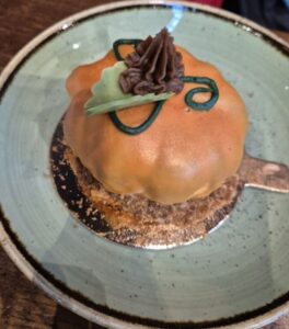 umpkin-shaped dessert with chocolate cream and green decorations on a green plate.