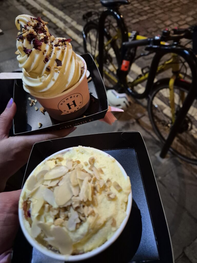 Two hands holding Humble Crumble desserts with various toppings.