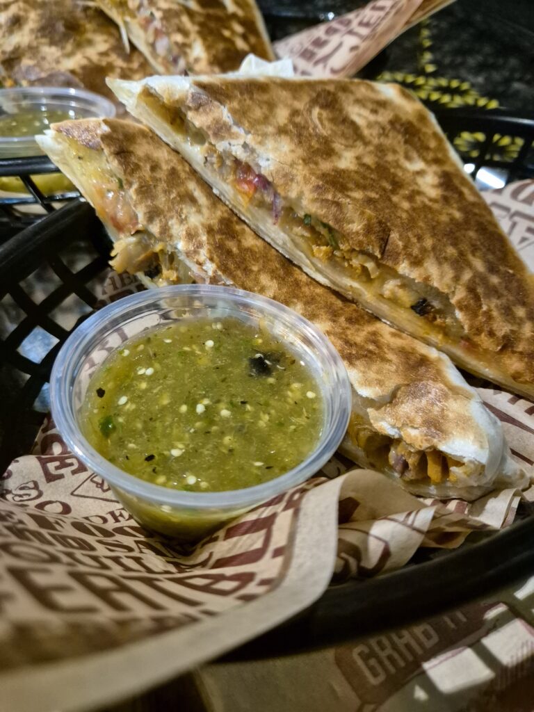 Quesadillas from Tortilla at Pancras Square served in a basket with a container of green salsa.