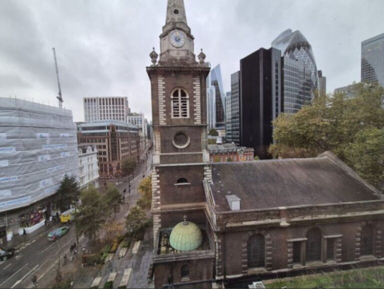 View from the hotel room with a historic church in the foreground and modern skyscrapers in the background, including a curved glass building.