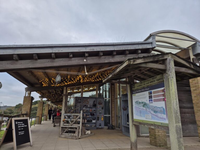 Entrance to the National Trust Visitor Centre Cafe at the White Cliffs of Dover, with welcoming signs and greenery.