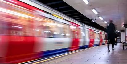 London Tube train departing from a station, slightly blurry as it speeds away.