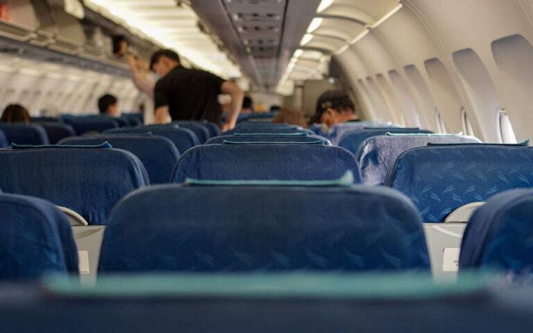 Showing the inside of an aircraft or an airplanes cabin with a few people onboard.