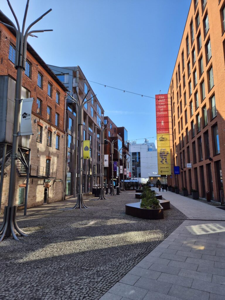 Modern urban street in Rotermanni Quarter in Tallinn City with tall brick buildings and colorful banners.
