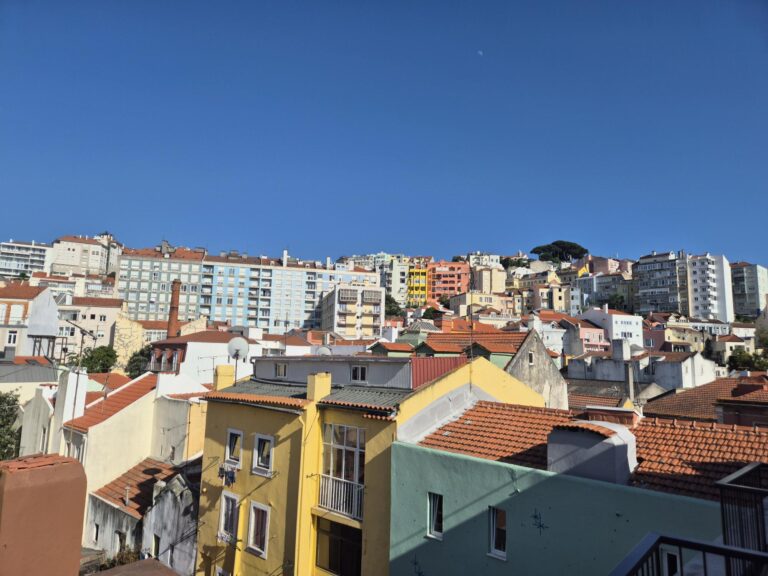 Cityscape view from Upon Angels’ Premium Studio room 505, showcasing colorful buildings under a clear blue sky.