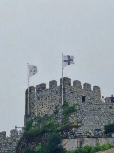 Crenellated wall of the Moorish Castle in Sintra with the Finnish flag vawing in the wind.