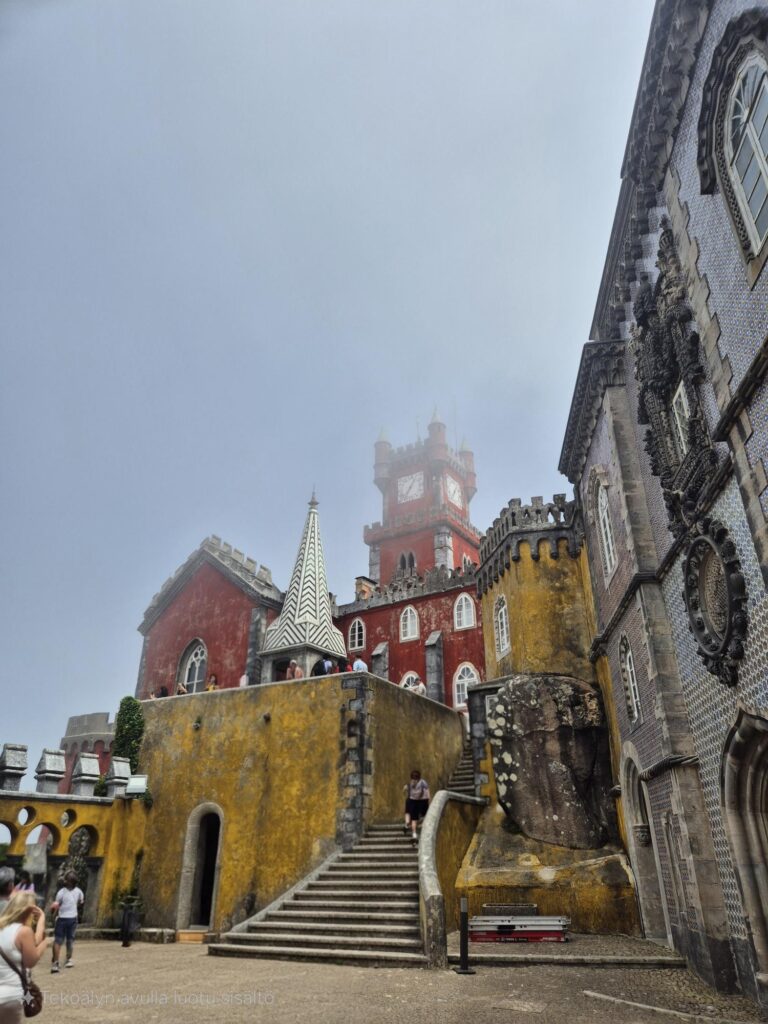 Pena Palace with colorful towers and walls, set against a misty backdrop that softens the surrounding landscape.