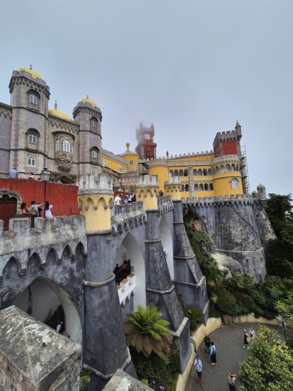 View of Pena Palace’s vibrant courtyard with yellow and red walls, arched windows, and decorative stonework.