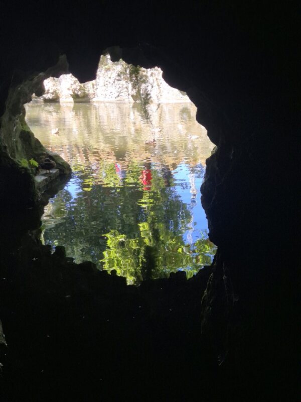Interior of a cave at Quinta da Regaleira with water and reflected light, surrounded by rugged stone.