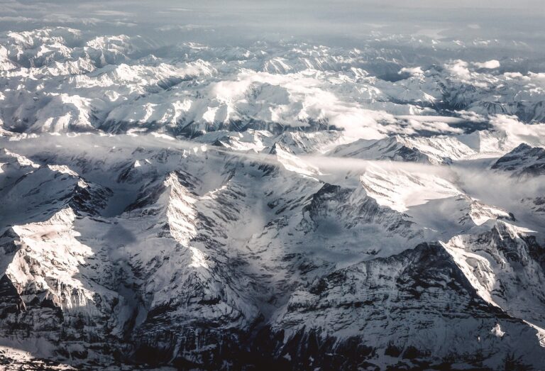 Luxury Christmas Holiday in the Swiss Alps with panoramic snow-covered mountain peaks under soft winter clouds.