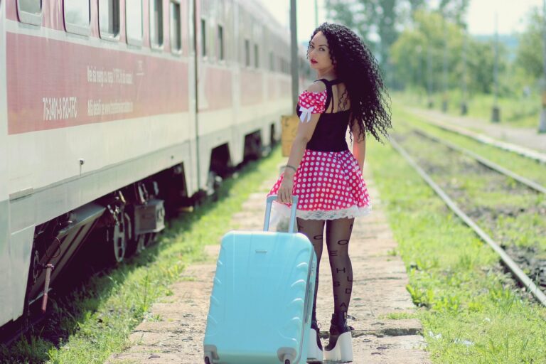 A traveler walking beside a train with a light blue rolling suitcase, demonstrating the idea of efficient packing tips for every type of trip.