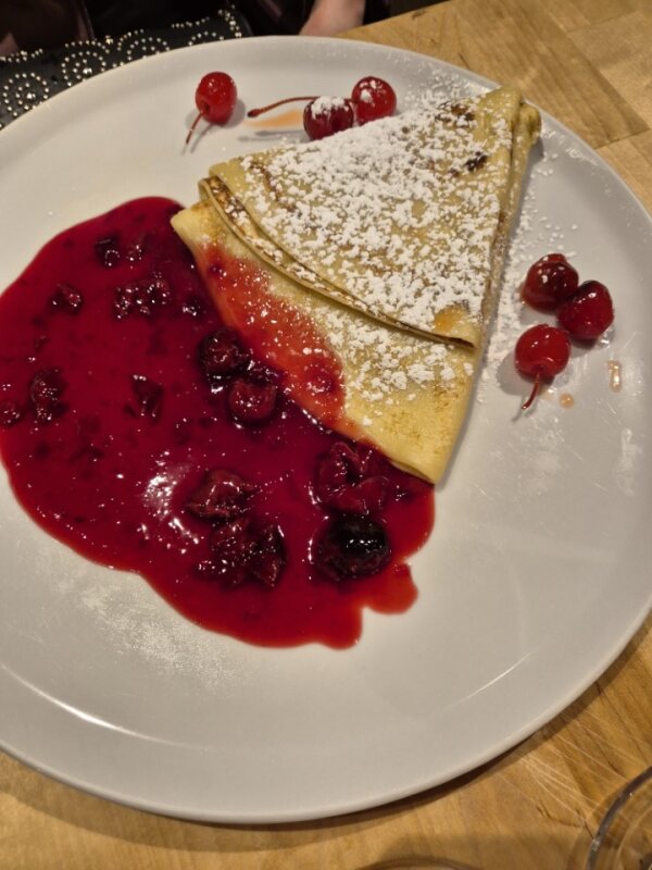 Sweet pancake with cherry sauce and powdered sugar at Pirmas Blynas in Vilnius