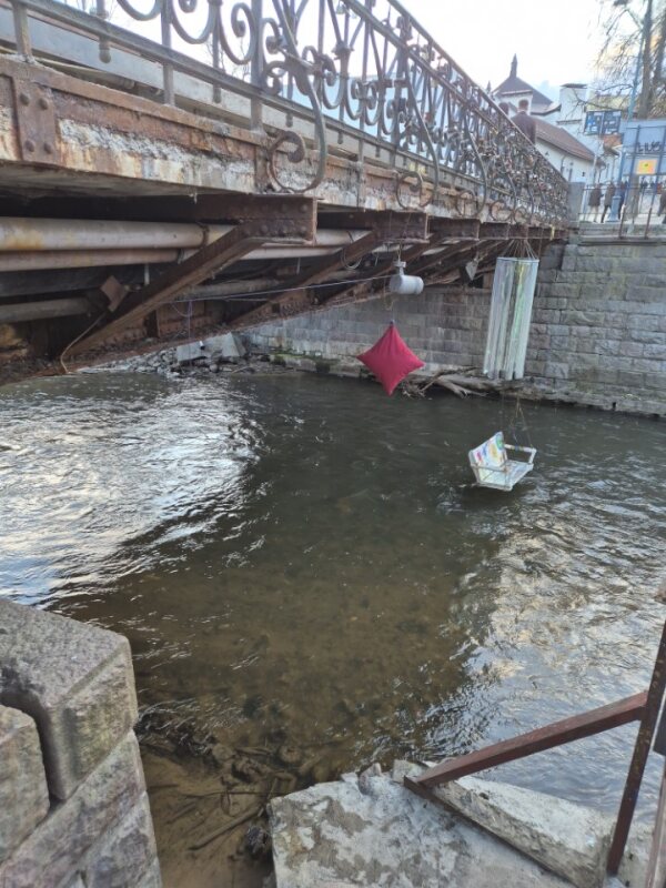 Riverside under a bridge with a hanging swing