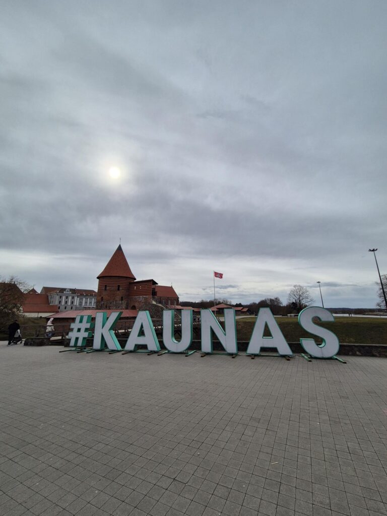 #KAUNAS sign with Kaunas Castle in the background.